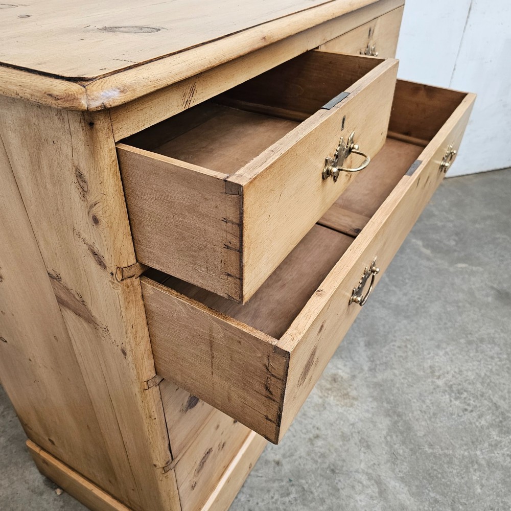 A Victorian light pine chest of drawers featuring a two-over-three drawer configuration, brass drop handles, keyholes, and a solid plinth base. View V