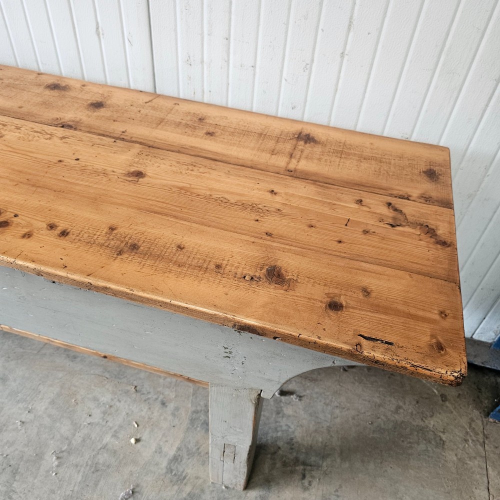 A long rustic pine worktable featuring a natural wood top, a light grey painted frame with a single drawer, and a lower shelf. View VII