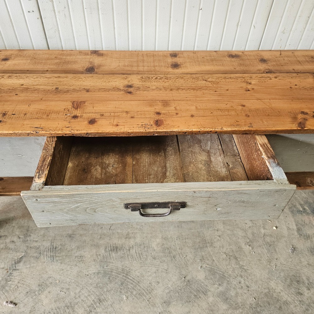 A long rustic pine worktable featuring a natural wood top, a light grey painted frame with a single drawer, and a lower shelf. View VIII