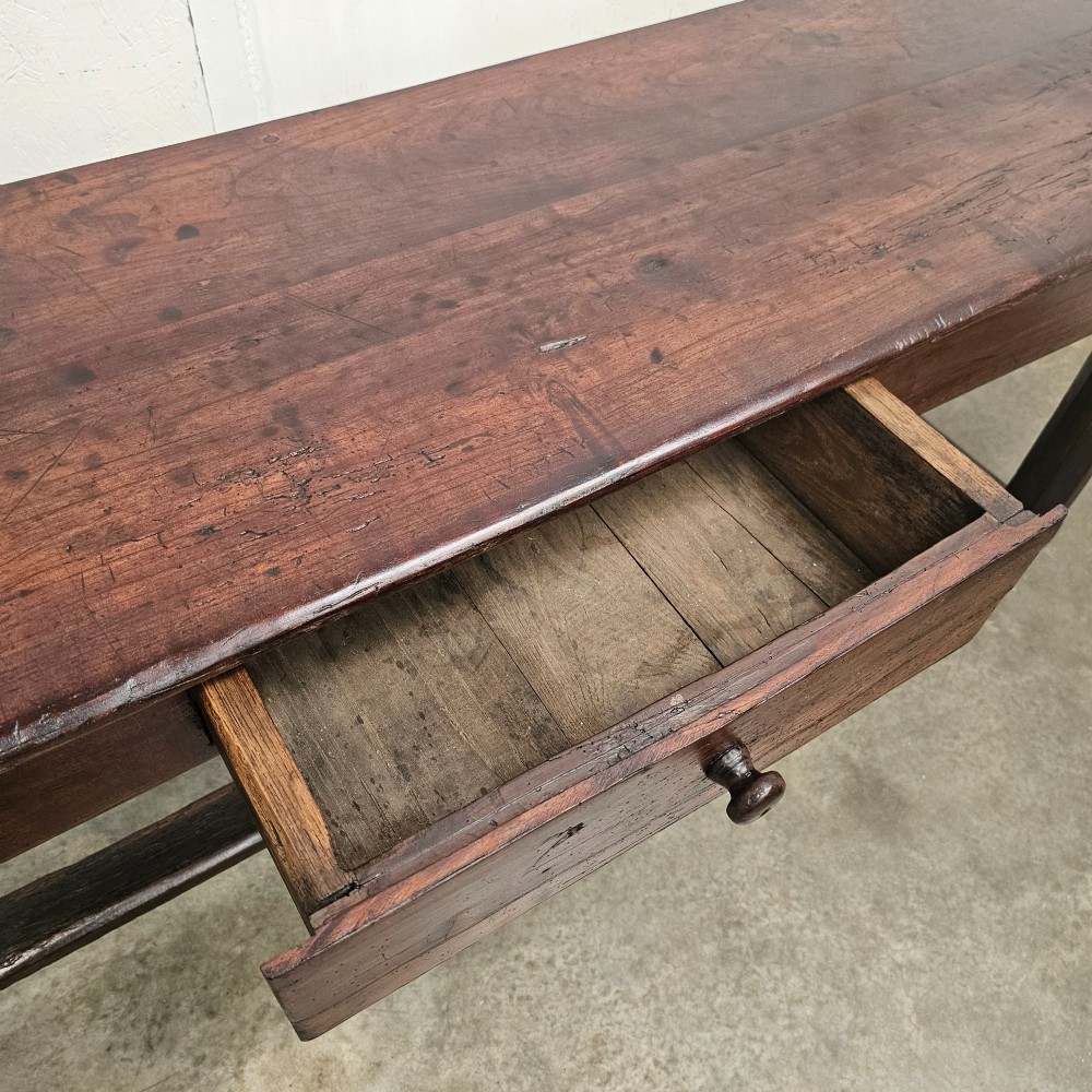 An antique dark fruitwood console table featuring a single central drawer, straight legs, and an H-stretcher base. View IV