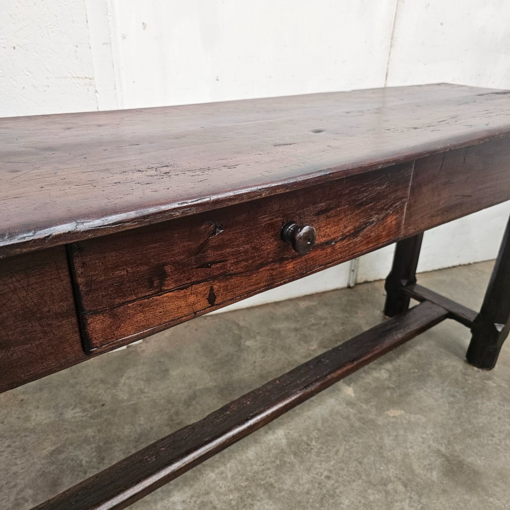 An antique dark fruitwood console table featuring a single central drawer, straight legs, and an H-stretcher base. View VI
