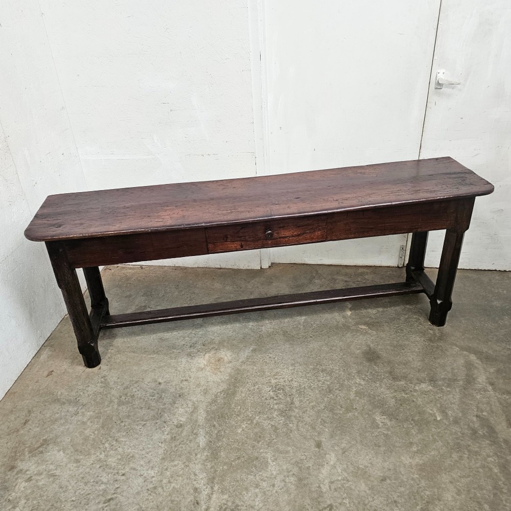 An antique dark fruitwood console table featuring a single central drawer, straight legs, and an H-stretcher base. View VII