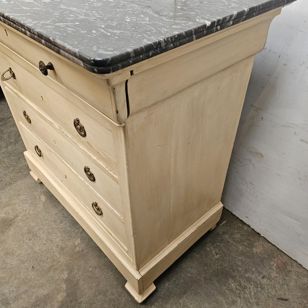 An off-white painted Louis Philippe chest of drawers with a dark marble top and brass ring handles. View IV