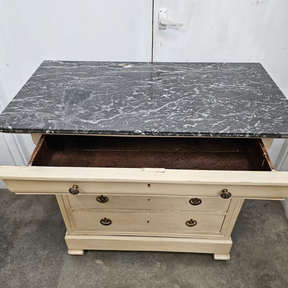 An off-white painted Louis Philippe chest of drawers with a dark marble top and brass ring handles. View V