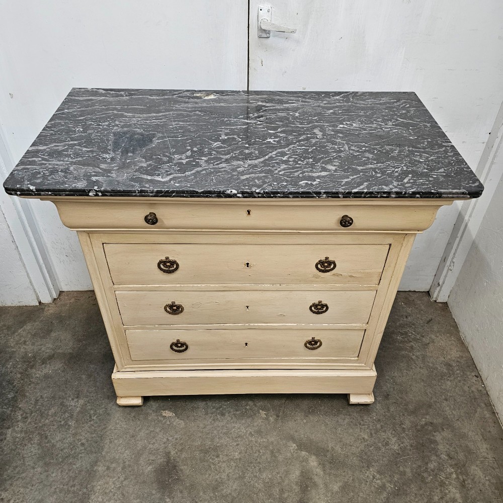 An off-white painted Louis Philippe chest of drawers with a dark marble top and brass ring handles. View IX