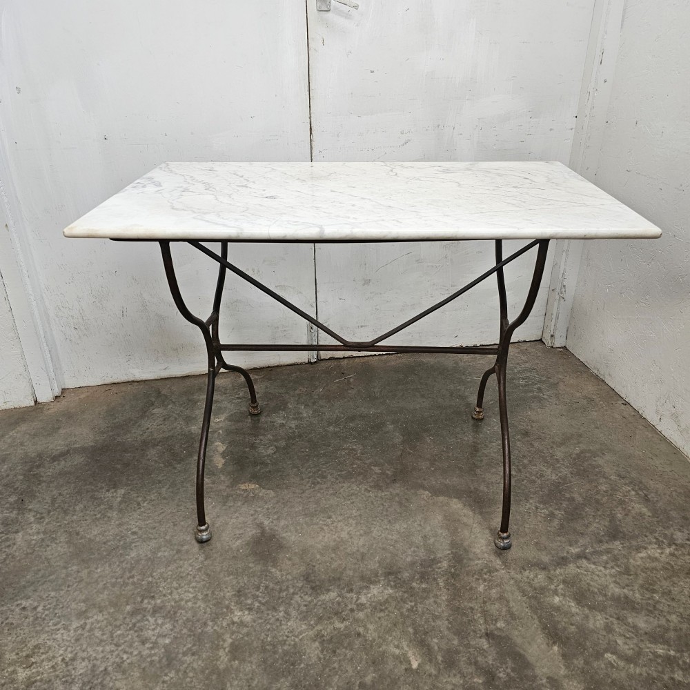 A rectangular white veined marble top resting on a dark wrought iron base with curved legs and cross-bracing.