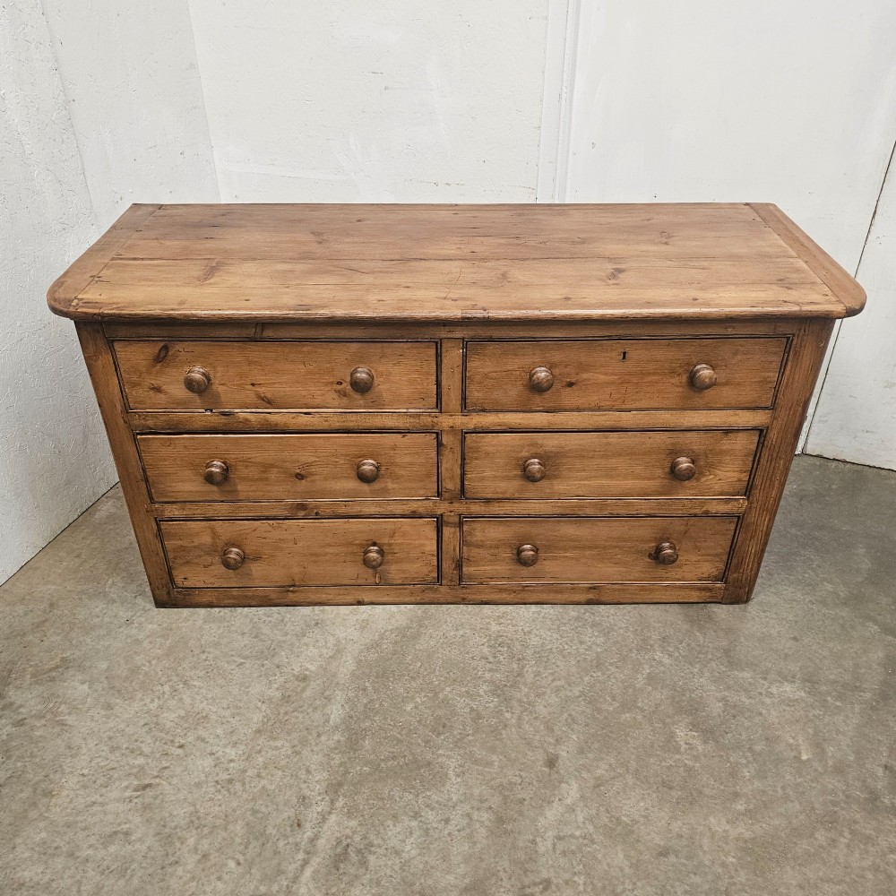A Victorian waxed pine bank of six drawers arranged in two columns with round turned wooden knobs and a plain plinth base. View V