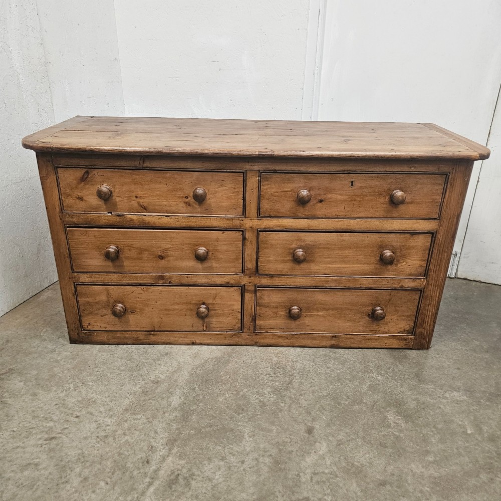 A Victorian waxed pine bank of six drawers arranged in two columns with round turned wooden knobs and a plain plinth base.