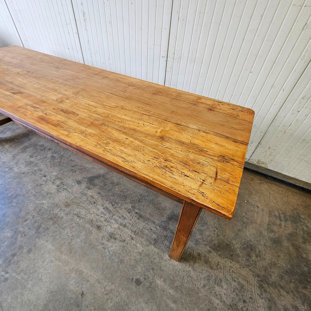 A long French country dining table crafted from beech and elm timber with a plank top and an H-stretcher base. View V
