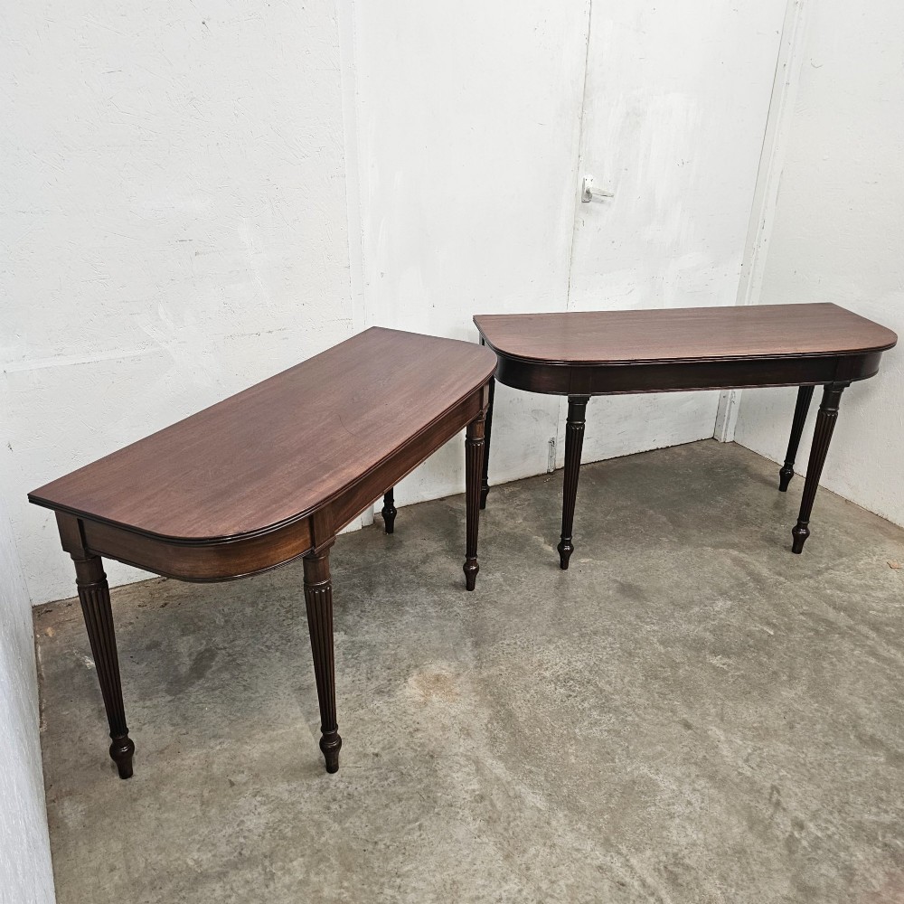 A pair of English mahogany console tables featuring D-shaped tops, subtle reeded aprons, and slender fluted tapered legs. View III