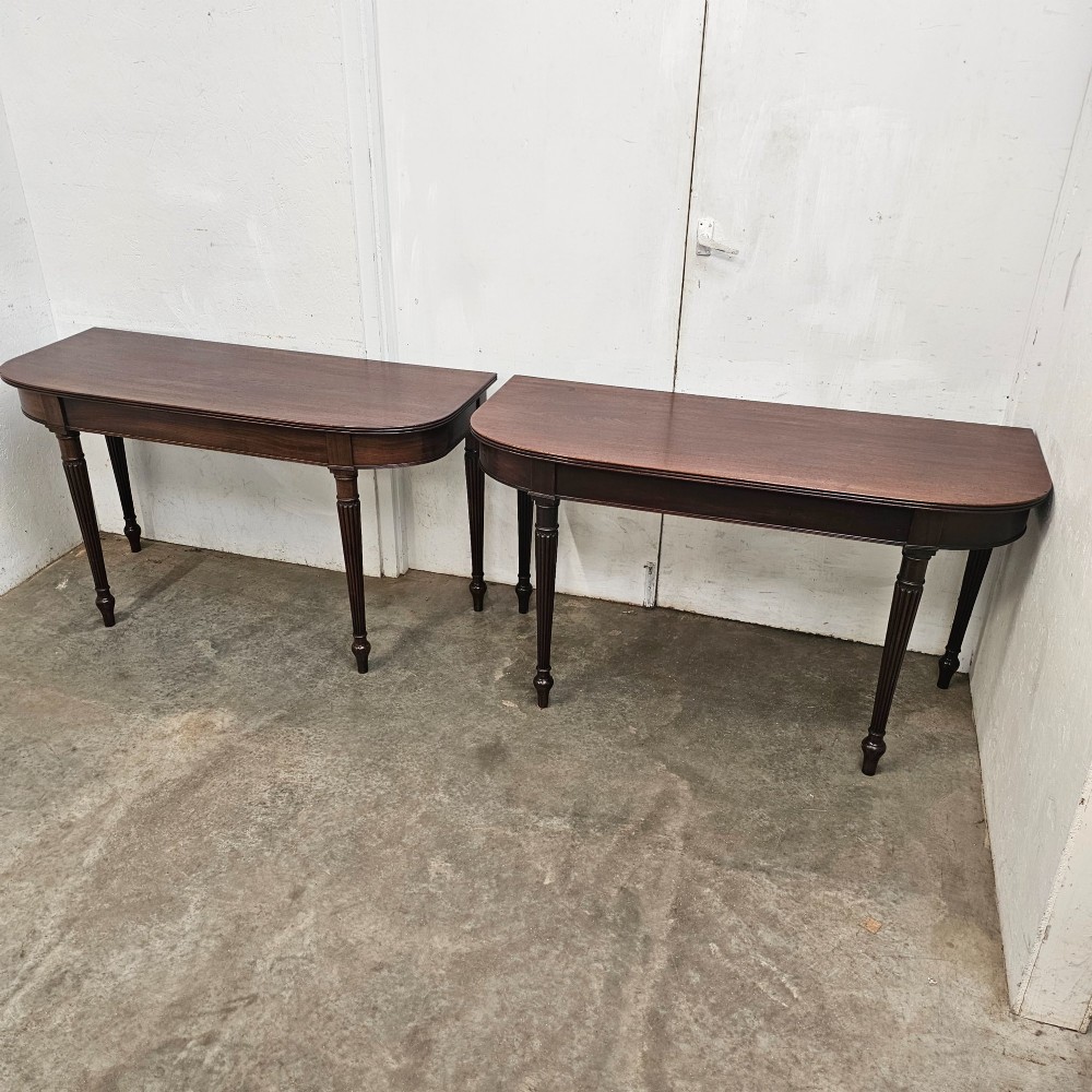A pair of English mahogany console tables featuring D-shaped tops, subtle reeded aprons, and slender fluted tapered legs. View IV