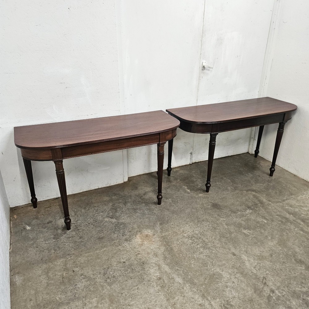 A pair of English mahogany console tables featuring D-shaped tops, subtle reeded aprons, and slender fluted tapered legs. View V