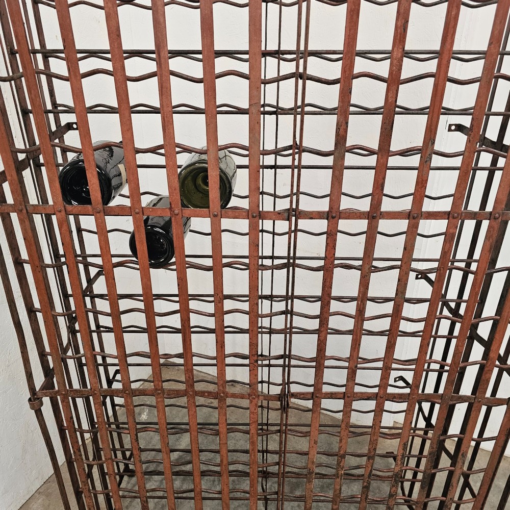 A large freestanding French steel wine rack featuring a open lattice riveted frame with multiple horizontal bottle tiers. View IV