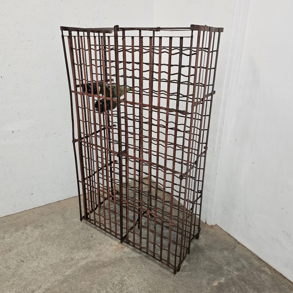 A large freestanding French steel wine rack featuring a open lattice riveted frame with multiple horizontal bottle tiers.