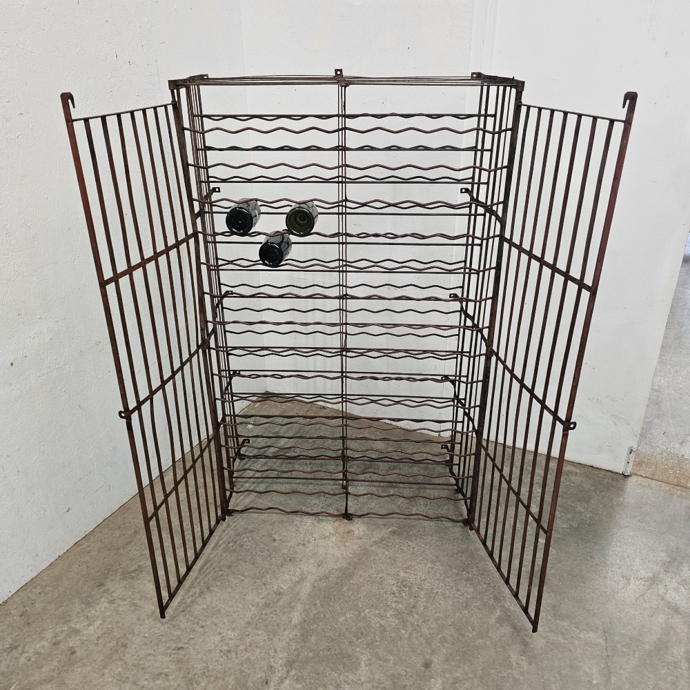 A large freestanding French steel wine rack featuring a open lattice riveted frame with multiple horizontal bottle tiers. View V