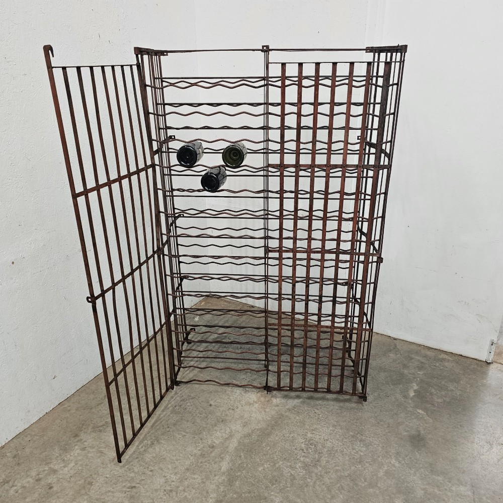 A large freestanding French steel wine rack featuring a open lattice riveted frame with multiple horizontal bottle tiers. View VI