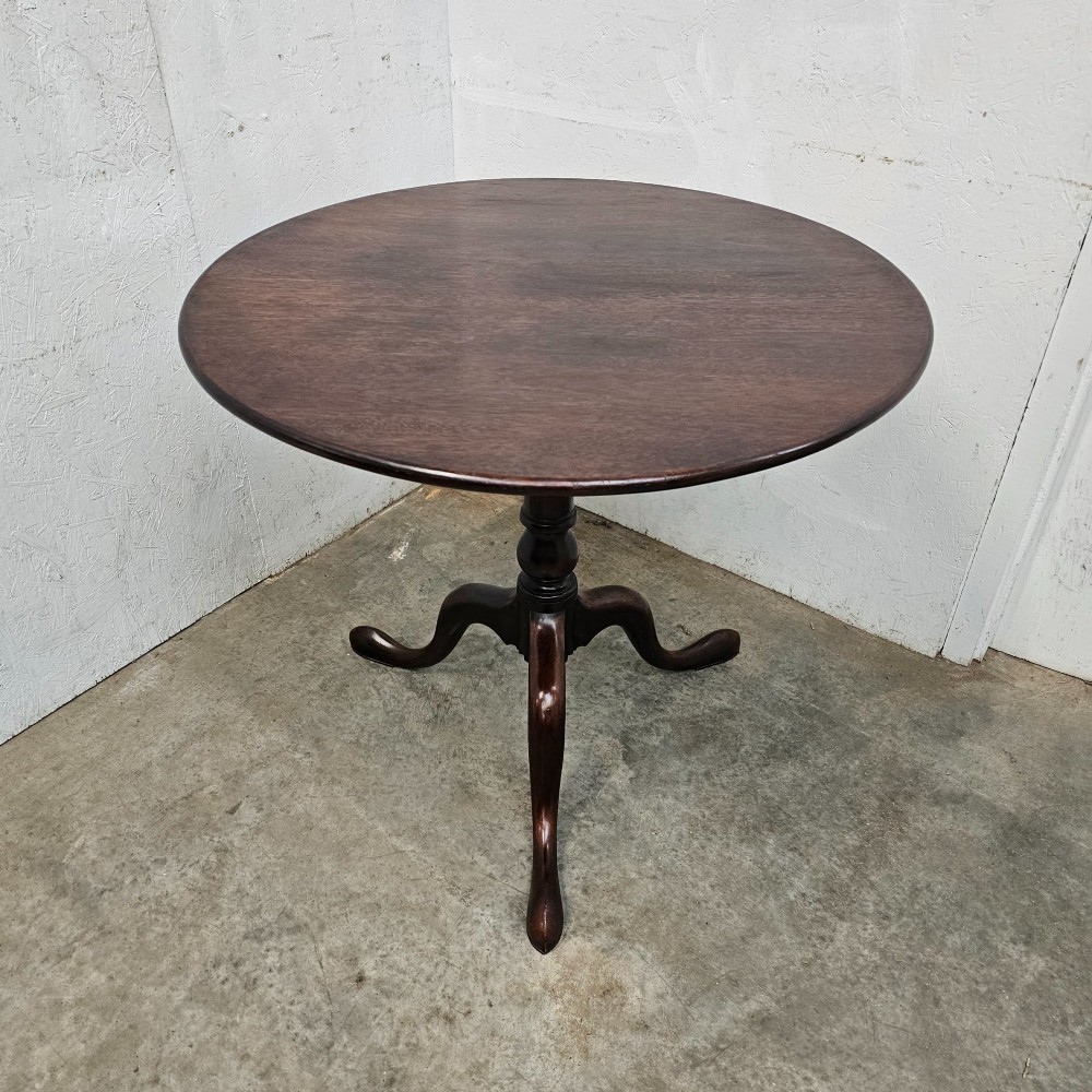 A Georgian dark mahogany wine table featuring a circular tilt-top surface supported by a turned baluster column and three cabriole tripod legs. View II