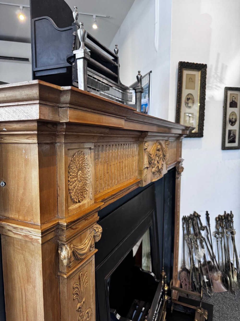 A Georgian carved wooden fireplace surround featuring a central figural relief tablet, fluted frieze, drapery swags, and classical pilasters. View II