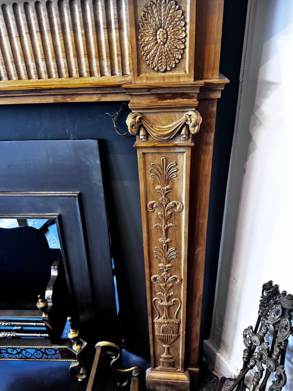 A Georgian carved wooden fireplace surround featuring a central figural relief tablet, fluted frieze, drapery swags, and classical pilasters. View VII