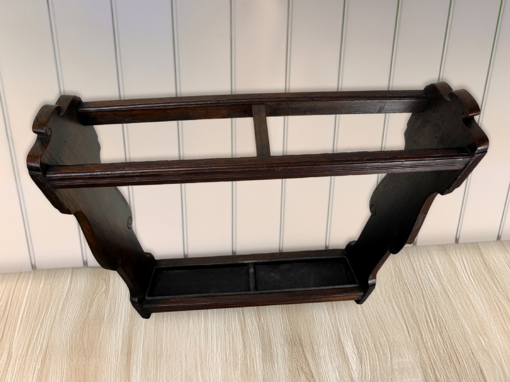 An Edwardian dark wood walking cane stand featuring a rectangular upper dividing frame, shaped side panels, and a twin-compartment drip tray at the base. View II