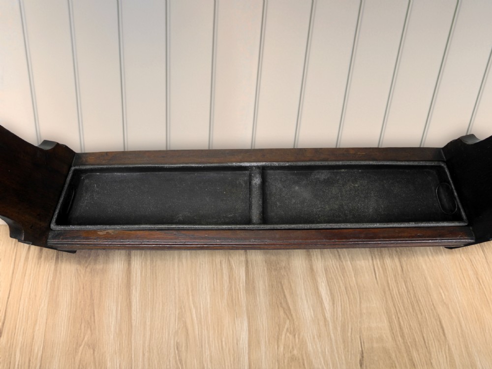 An Edwardian dark wood walking cane stand featuring a rectangular upper dividing frame, shaped side panels, and a twin-compartment drip tray at the base. View III