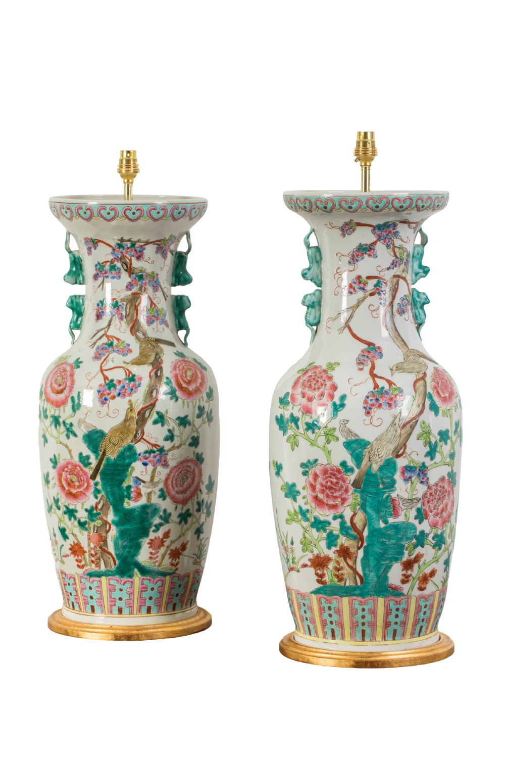A pair of 20th-century Chinese Famille Rose porcelain vases mounted as table lamps with brass fittings on gilded round wooden bases, decorated with painted birds and flowers.