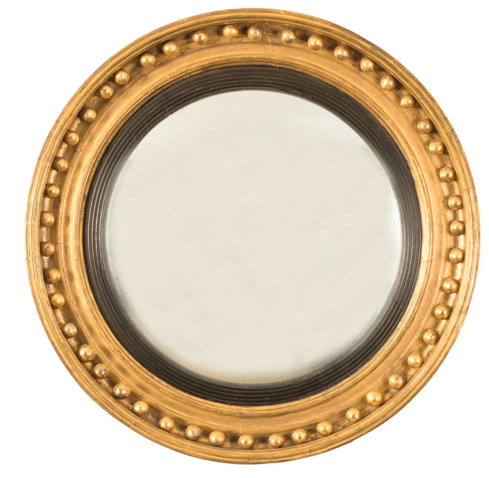 A circular Regency convex wall mirror featuring a giltwood frame decorated with ball moulding and an ebonised reeded inner slip.