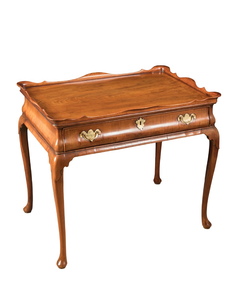An 18th-century George III mahogany silver table featuring a tray-top scalloped gallery, cabriole legs with pad feet, and a single drawer with brass handles.