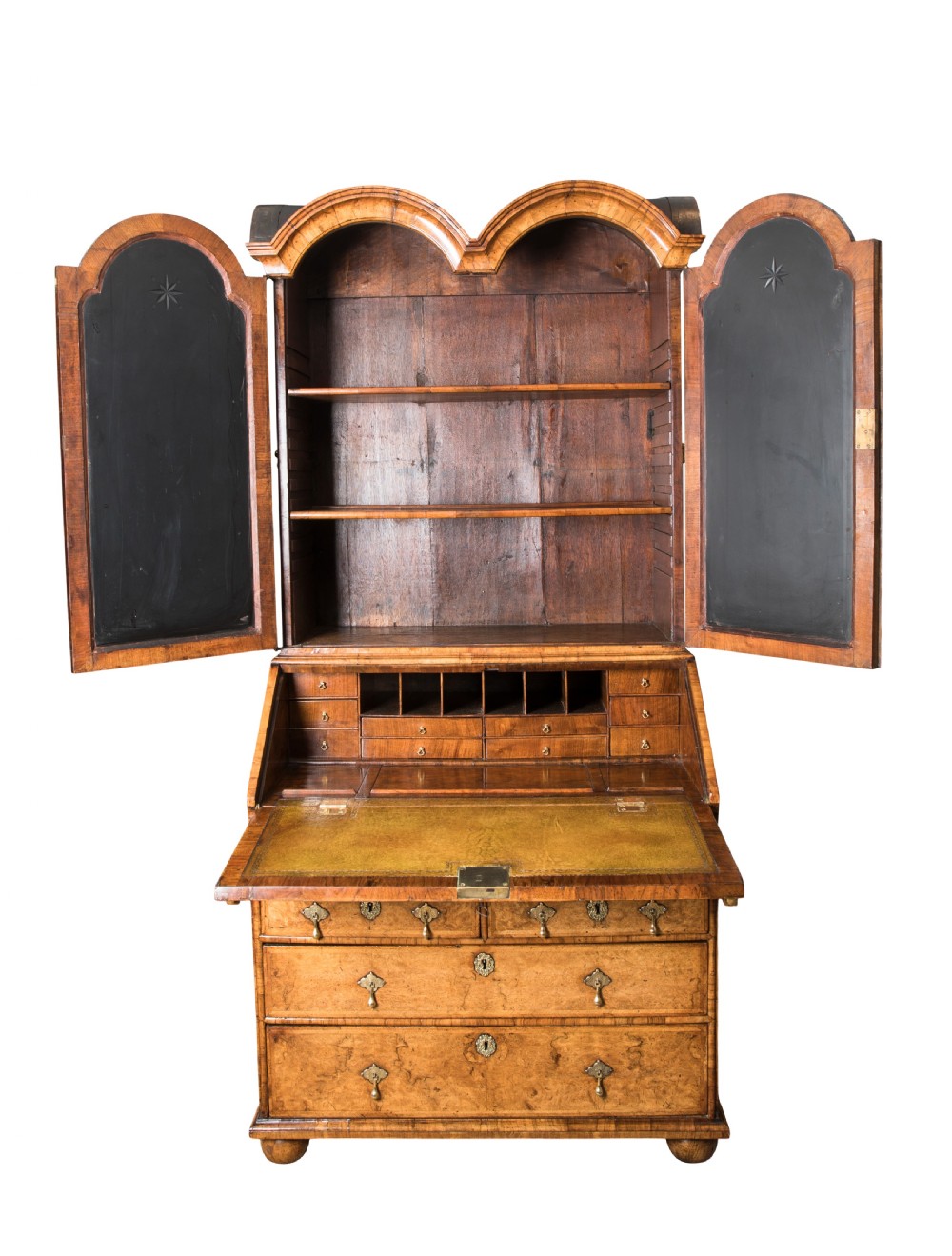 An antique George I walnut bureau bookcase featuring an open double-domed upper cabinet, an angled fall-front desk with leather writing slope, interior pigeonholes, and lower chest drawers with brass handles.