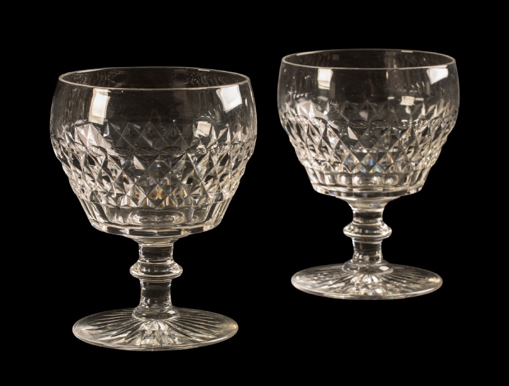 A pair of clear cut crystal rummer glasses featuring diamond-cut patterns around the bowl, turned stems, and starburst cut circular bases.