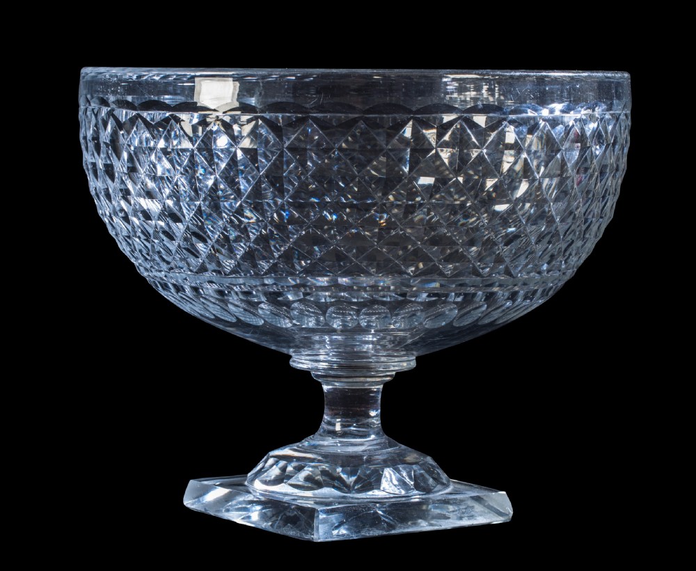 An early 19th-century clear cut-glass pedestal bowl featuring a diamond hobnail pattern and a square base.