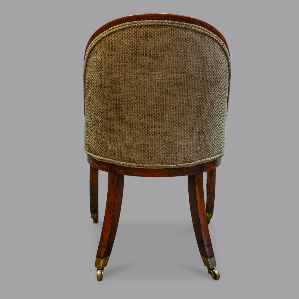 A pair of low-backed Regency mahogany slipper chairs featuring curved wooden frames, upholstered seats and backs, and sabre legs with brass castors. View IV