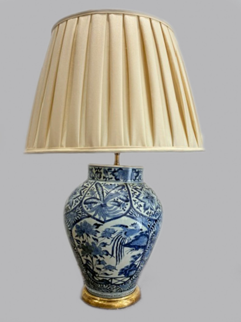 A late 17th-century Japanese blue and white porcelain vase featuring hand-painted floral and avian motifs, mounted on a gilt base as a table lamp with a cream pleated lampshade.