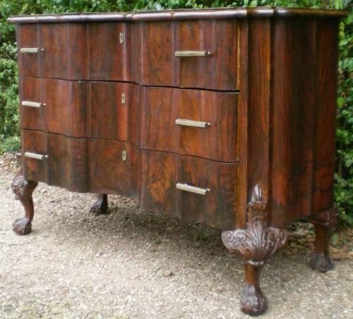 fig 1. A walnut chest of drawers featuring a shaped serpentine front, three drawers with brass handles, keyhole escutcheons, and carved cabriole legs.