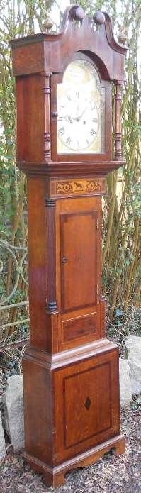 fig 1. An antique Victorian oak longcase clock featuring a swan-neck pediment, marquetry inlay with a horse motif, and an arched dial with Roman numerals.