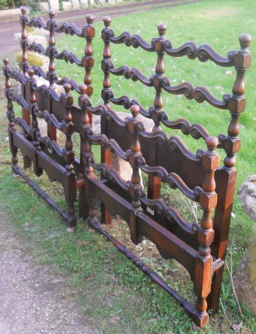fig 1. A pair of dark oak single bed headboards featuring horizontal wave-shaped carved rails and turned vertical spindles.