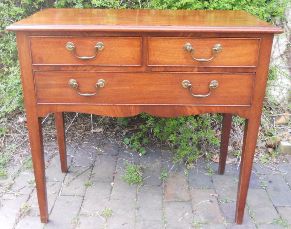 A Georgian mahogany side table featuring two upper drawers and one lower drawer with brass handles on tapered legs.