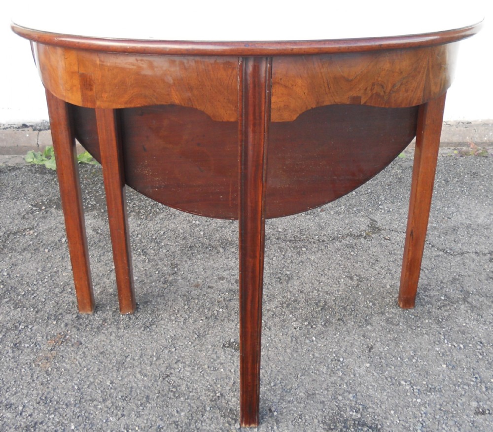 A Georgian mahogany drop-leaf side table featuring tapered legs and a curved apron.