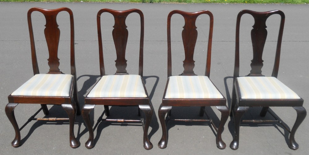 A set of four dark mahogany highback dining chairs featuring vase-shaped splats, cabriole legs, and striped upholstered drop-in seats.