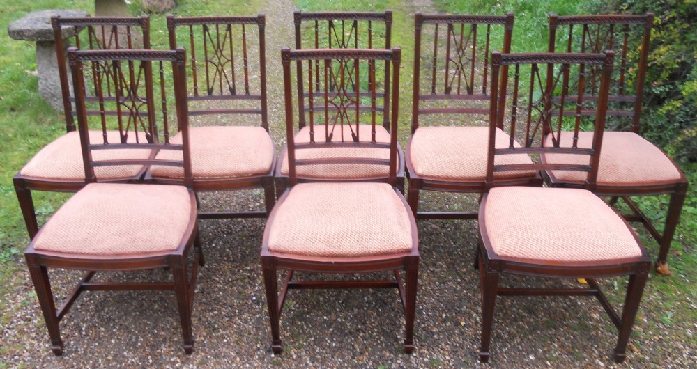 A set of eight dark mahogany dining chairs featuring carved lattice backs, square tapered legs, and peach fabric upholstered seats.