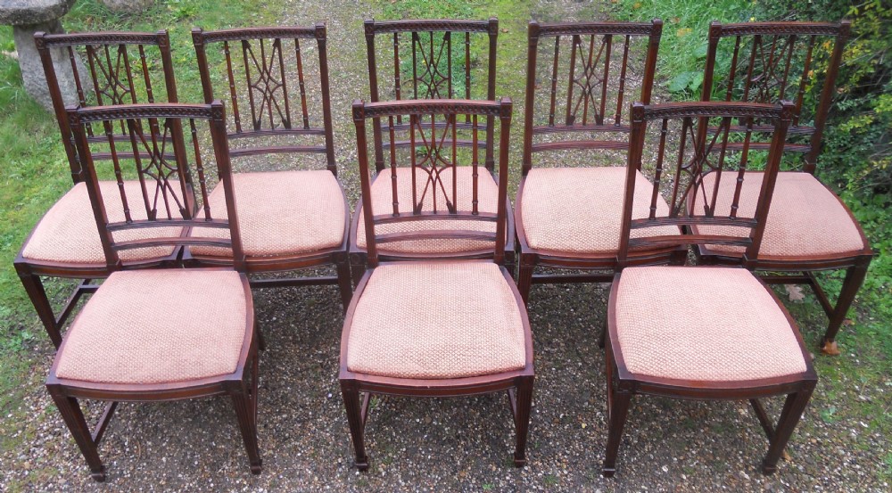 A set of eight dark mahogany dining chairs featuring carved lattice backs, square tapered legs, and peach fabric upholstered seats. View III