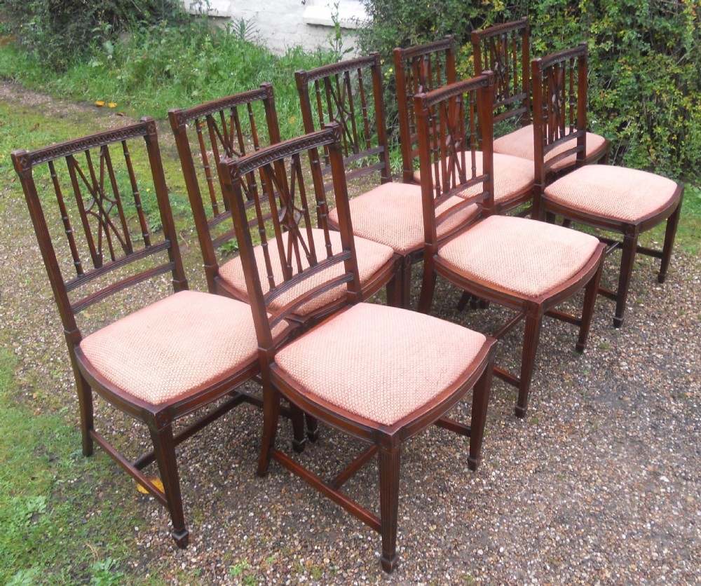 A set of eight dark mahogany dining chairs featuring carved lattice backs, square tapered legs, and peach fabric upholstered seats. View V