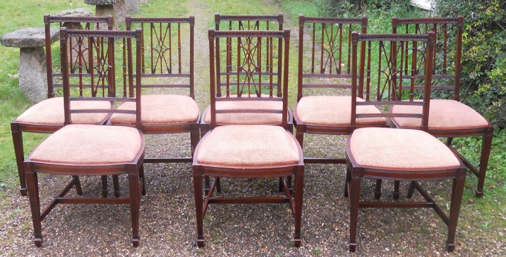 A set of eight dark mahogany dining chairs featuring carved lattice backs, square tapered legs, and peach fabric upholstered seats. View VI