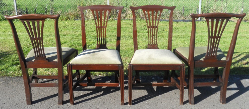 A set of four Georgian mahogany dining chairs featuring vertical pierced back splats, straight reeded front legs, and padded light-coloured seats. View V