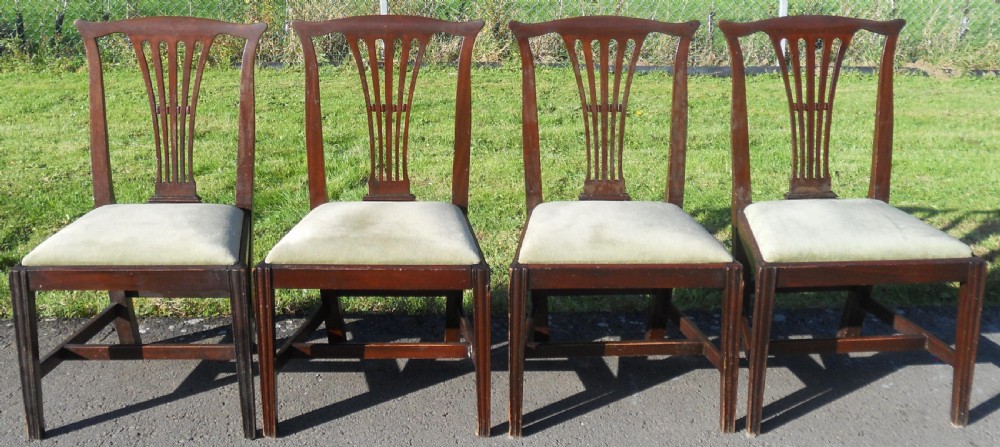 A set of four Georgian mahogany dining chairs featuring vertical pierced back splats, straight reeded front legs, and padded light-coloured seats. View VI