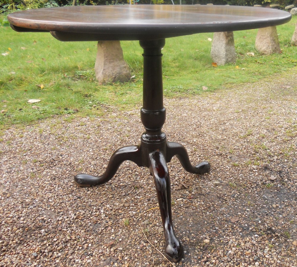 A Georgian mahogany supper table with a polished circular top, turned pedestal stem, and three cabriole legs terminating in pad feet. View V