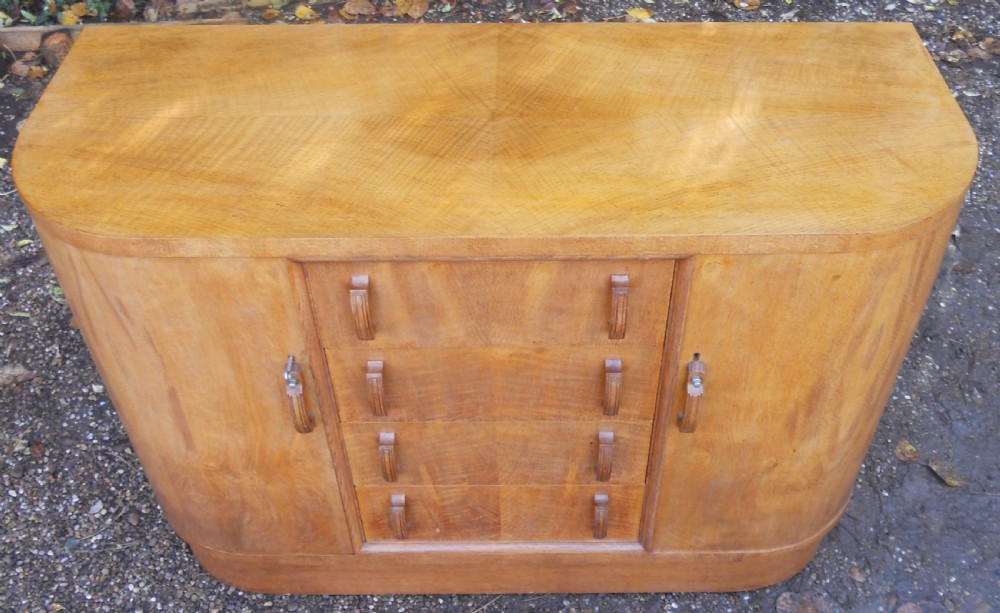 An Art Deco walnut sideboard featuring a central column of four drawers flanked by curved cupboard doors on a solid plinth base. View IV