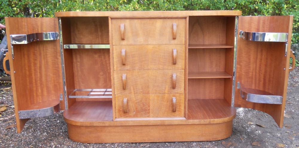 An Art Deco walnut sideboard featuring a central column of four drawers flanked by curved cupboard doors on a solid plinth base. View VI