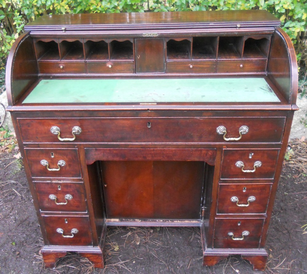 A small Georgian mahogany pedestal desk featuring a flexible slatted tambour rolltop cover, multiple drawers with brass swan-neck handles, and bracket feet. View VIII