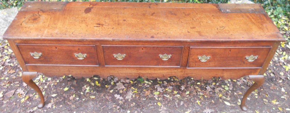 A Georgian oak kitchen dresser featuring three base drawers, cabriole front legs, brass handles, and an upper rack with shelves flanked by cupboard doors. View VIII